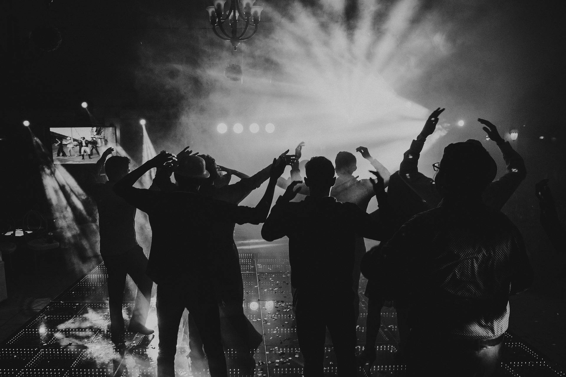 a black and white photo fo a group of people dancing in a club